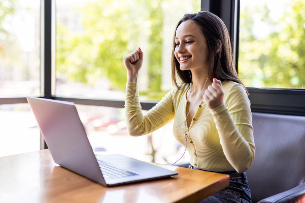 Best Website Design Company for Cleaning Services 4 smiling-happy-businesswoman-headphones-sits-desk-looks-laptop-screen-making-notes-participating-self-improvement-webinar