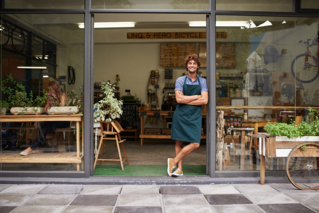 happy-arms-crossed-portrait-man-restaurant-small-business-coffee-shop-waiter-entrepreneur-welcome-smile-with-male-barista-front-door-cafe-diner-food-industry