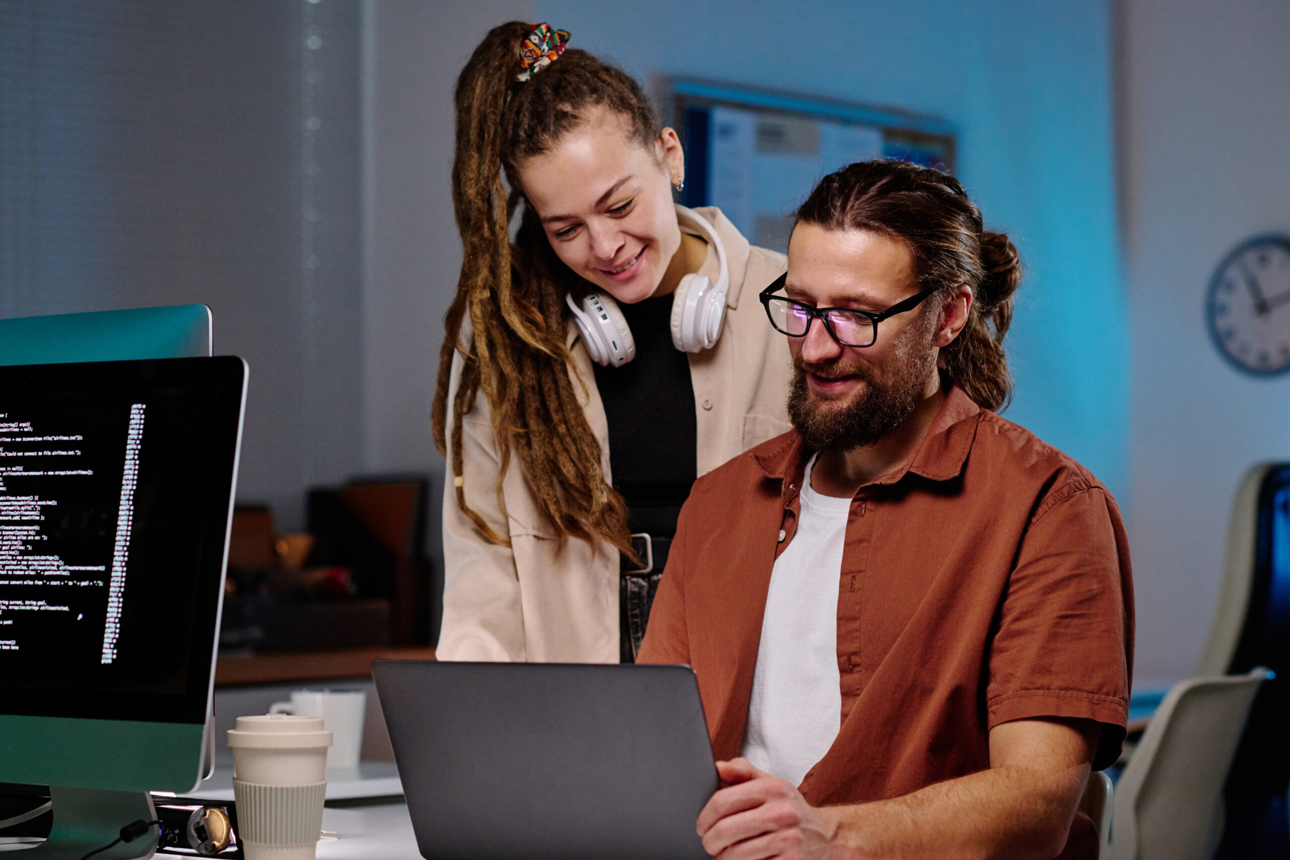 Two happy young programmers looking at laptop screen with coded data